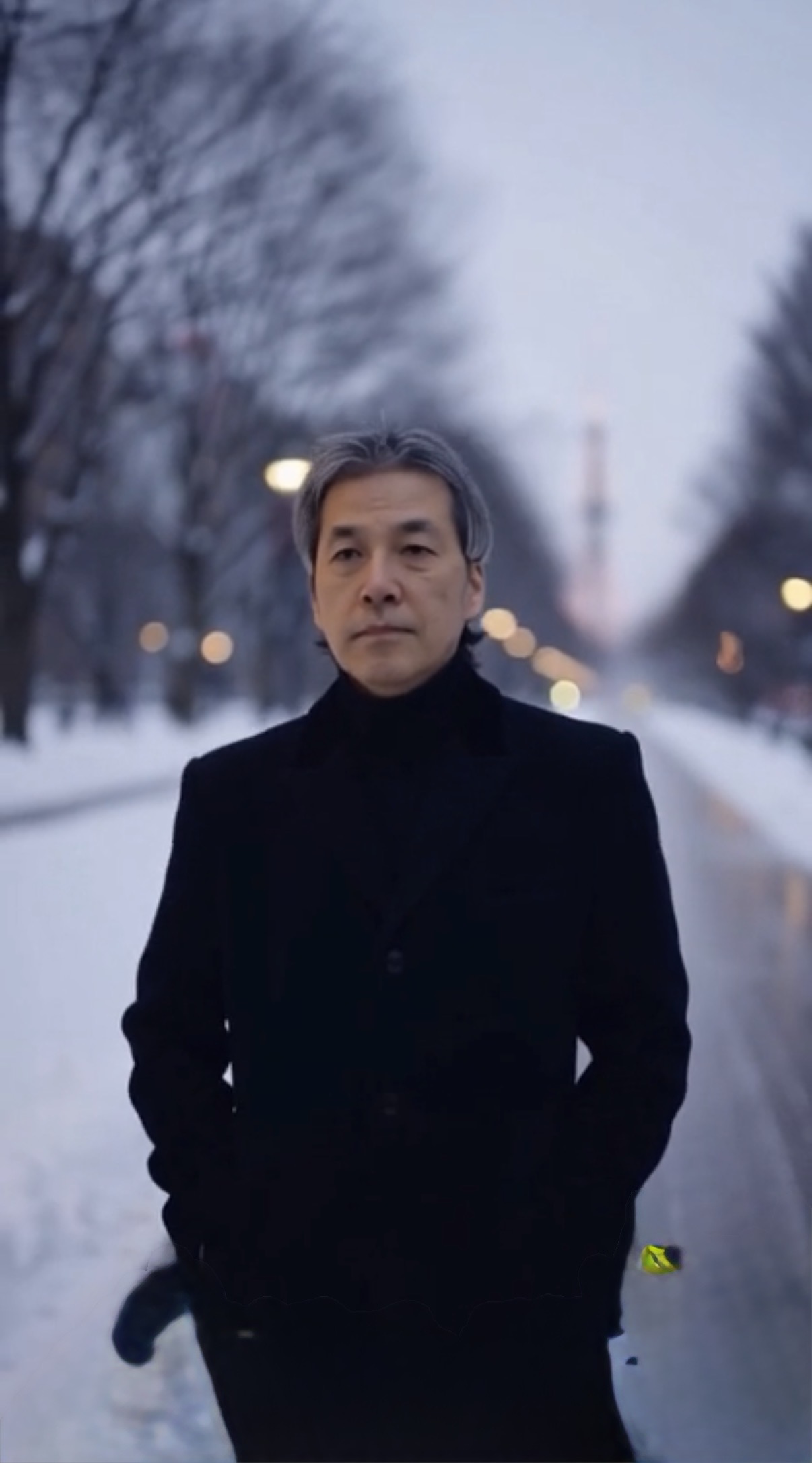 January M Itzki in a black coat on a snow-covered avenue in Sapporo